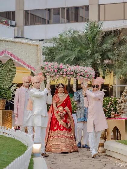 The bride's entrance under a phoolon ki chaadar designed to match the mandap decor, featuring a dense arrangement of pink flowers.