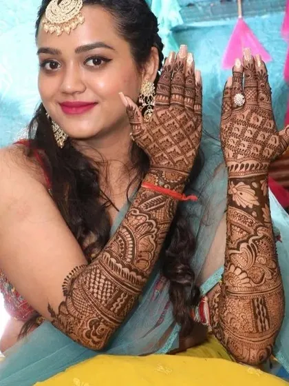 The same bride showing the back of her hands, which feature a beautiful and intricate 'jaal' (net) pattern that complements the front design.