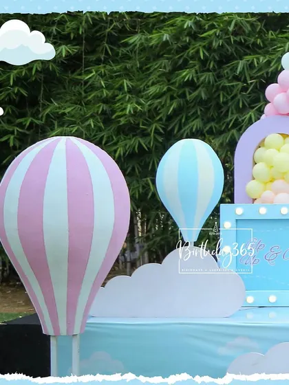 A close-up of the charming hot air balloon props from a pastel-themed party. These large, freestanding props in pink and blue add a wonderful sense of whimsy and adventure to the decor.