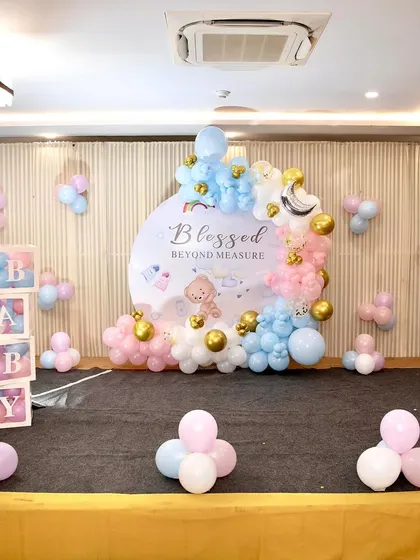 A wider view of the "Blessed Beyond Measure" baby shower stage, showing the backdrop, balloon arrangements, and decorative "BABY" blocks.