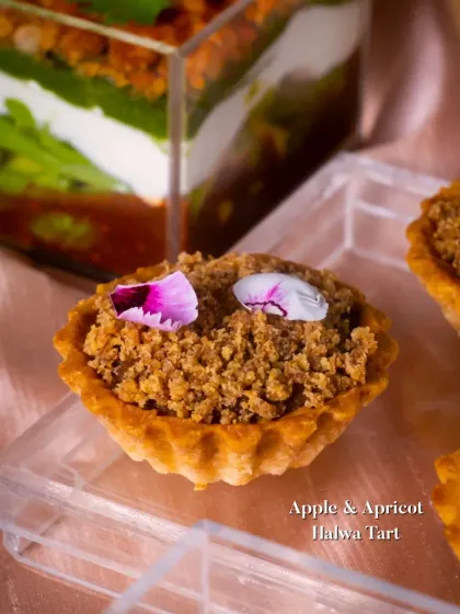 An Apple & Apricot Halwa Tart, featuring a crumbly topping and delicate edible flower petals. A perfect fusion of Indian and Western dessert concepts.