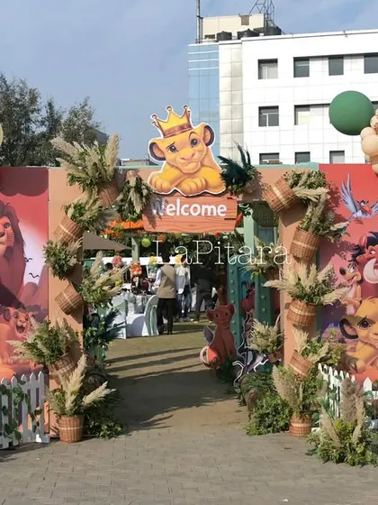 The main entrance arch for the Lion King party, featuring a large 'Welcome' sign and an array of character and animal props.