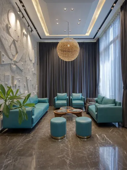 A formal drawing room with teal leather sofas set against a custom-designed, three-dimensional geometric art wall. A large rattan pendant light adds a touch of organic texture.