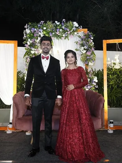 The couple posing against their beautiful reception decor. Her elegant red gown and my soft glam makeup create a perfectly coordinated look.