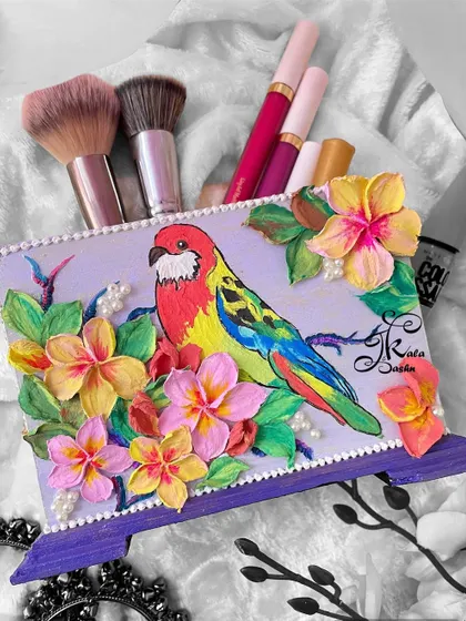 Art can be functional too. This multipurpose utility stand, featuring a brightly painted macaw amidst tropical flowers, is perfect for holding makeup brushes, cutlery, or pens. It’s a cheerful and practical piece to brighten your desk or vanity.