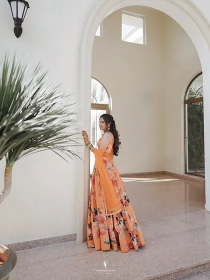 A serene portrait of the bride in her orange floral lehenga, taking a quiet moment during her Haldi ceremony.