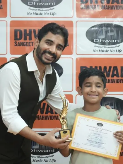 A teacher presents an award to his smiling student.