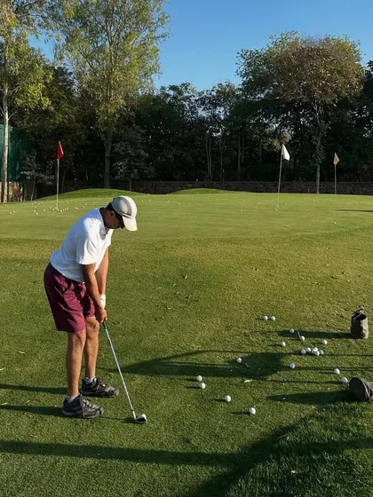 A golfer practices his chipping, surrounded by balls, ready for a long session of focused work.