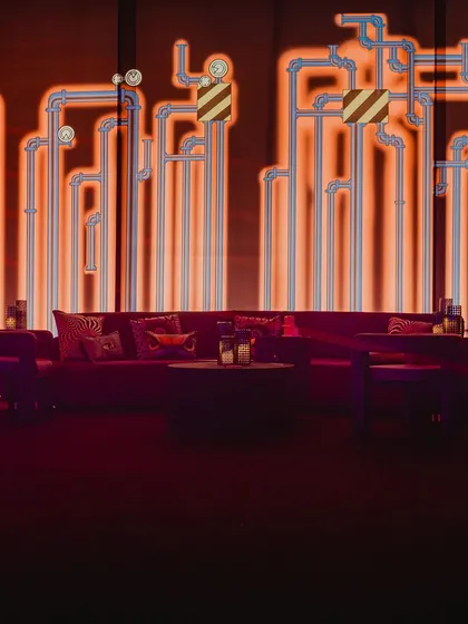 Even the lounge areas were on-theme. We used a purple velvet sofa set against a backlit wall with a graphic pipe design, creating a cool, industrial-chic vibe.