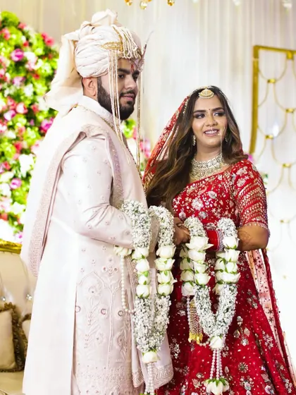 The moment of acceptance during the Varmala ceremony. This classic shot captures the couple in their beautiful wedding attire, holding the garlands that symbolize their union in a North Indian Hindu wedding.