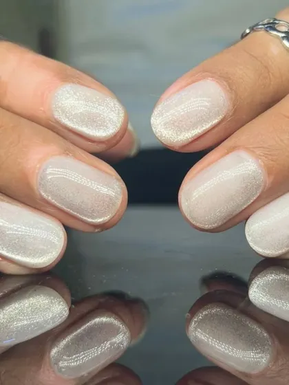 A beautiful, shimmery white cat-eye polish on short, rounded nails for a subtle and magical look.