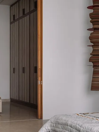 A view from the parent's bedroom towards the ensuite bathroom, showcasing the clean lines, warm wood wardrobe, and neutral color palette.