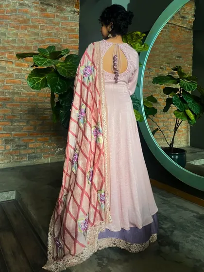 The back of this lilac Anarkali suit features a delicate keyhole design and tassels, complementing the beautiful floral dupatta.