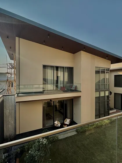A view of the cantilevered balcony and large glass windows of the Chhattisgarh home. The design emphasizes open, light-filled spaces and a strong connection between the interiors and the surrounding green areas.