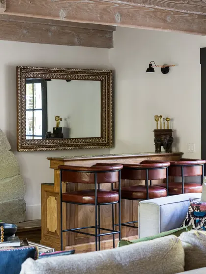 The bar area in the Saratoga home is a cozy corner for entertaining. We used warm wood for the bar, paired with classic leather stools. The ornate mirror and exposed ceiling beams add layers of texture and character to this intimate space.
