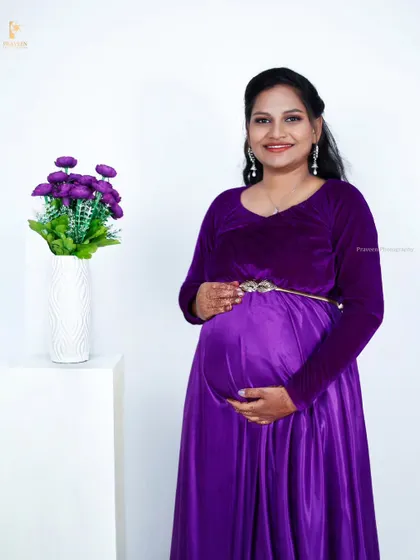 A classic studio portrait in the purple velvet and satin maternity gown. The simple white background makes the vibrant purple color pop.