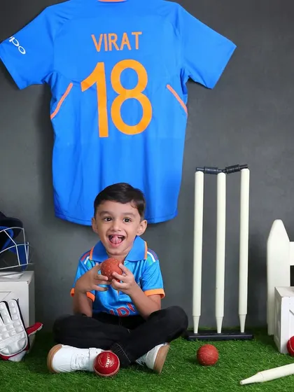A future cricket star. This toddler is having a blast in our cricket-themed setup, complete with a Virat Kohli jersey, bat, ball, and wickets.