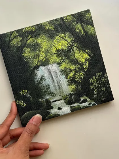 A slightly different angle of me holding the finished waterfall canvas, showing the clean edges and the depth of the forest.