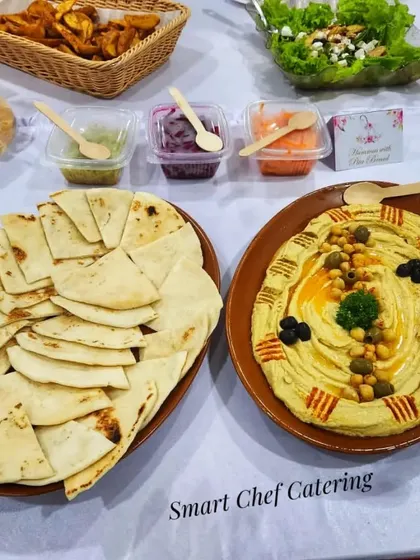 A delicious spread for a Thanksgiving dinner party. This setup includes creamy hummus with pita bread, fresh salad, and crispy potato wedges.