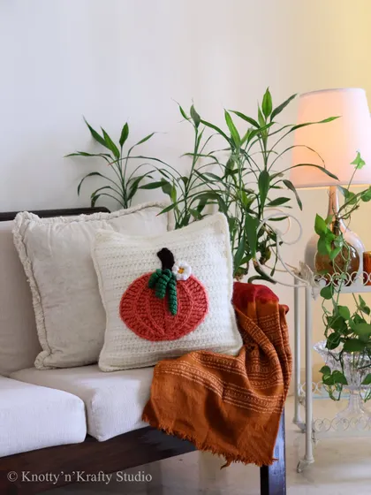 An autumn-inspired pumpkin crochet cushion, adding a touch of seasonal warmth to a simple, elegant sofa. It's a small detail that makes the whole room feel cozier.