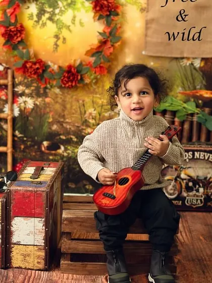 A little musician in the wild. The tiny ukulele adds a playful element to this rustic, explorer-themed photoshoot.