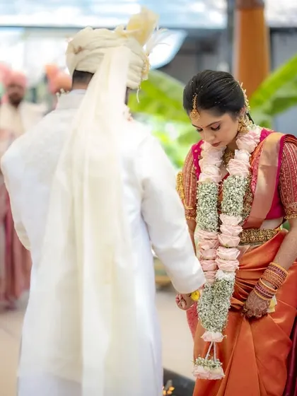 A quiet moment during the wedding ceremony. The bride and groom hold hands, a simple gesture of connection and support amidst the rituals.