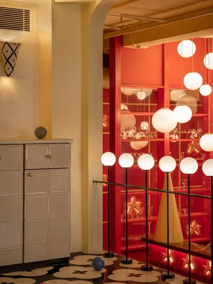 Another view of the playful details at Masala, where custom cabinetry with textured fronts stands against a backdrop of glowing red shelves. Every element is designed to contribute to a rich, layered sensory experience.