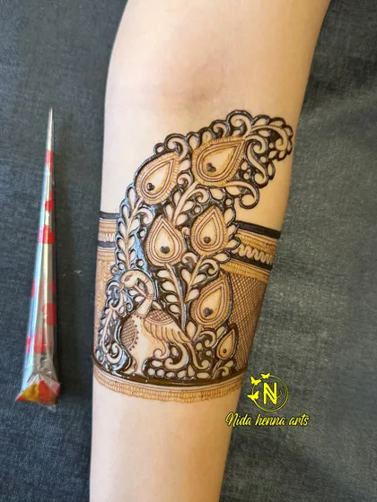 This shows the peacock cuff band on the upper arm, created with fine lines and detailed shading. I often use a henna cone to show the scale and freshness of the paste.