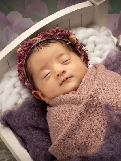 I focus on creating a safe and peaceful environment for your little one. This classic posed newborn portrait captures the serene beauty of a sleeping baby, nestled comfortably in a miniature white cot.