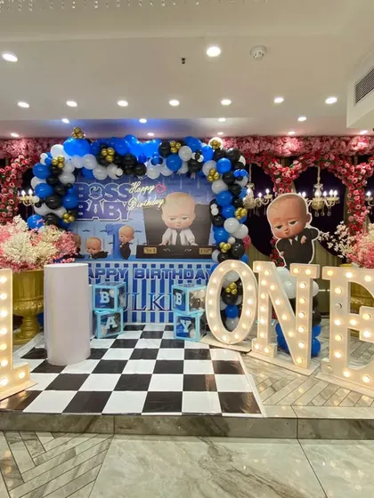 This Boss Baby theme combines a balloon arch with a beautiful pink floral background, creating a unique and elegant look for a first birthday party.