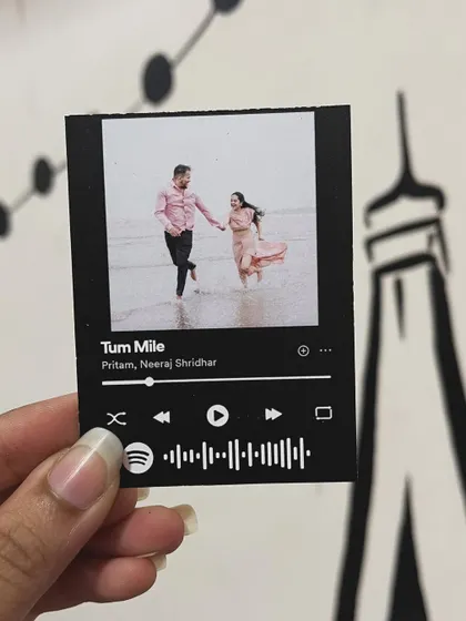 A pre-wedding shoot photo on the beach paired with the romantic song "Tum Mile" on a Spotify card.