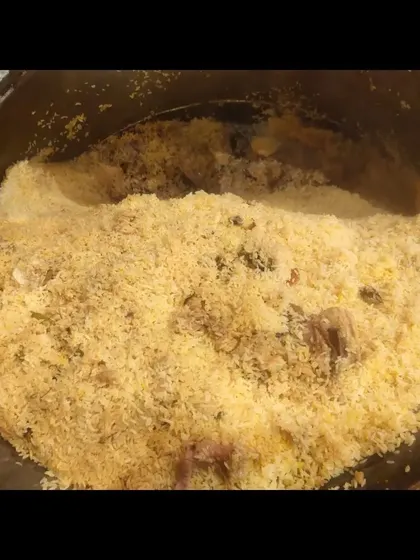 A look inside the degh. The layers of rice and meat are clearly visible, ready to be mixed and served.