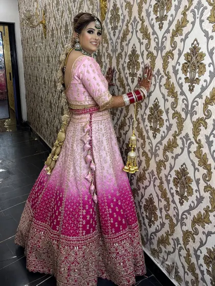 A full-length shot showing the stunning ombre effect of her lehenga. The hairstyle is a beautiful, intricate braid that complements the entire look.