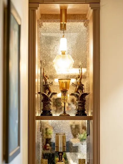 A close-up of a custom-designed display niche. We used an antique mirror for the back panel and integrated a pendant light to highlight the client's treasured collectibles, creating a small, jewel-box-like feature.