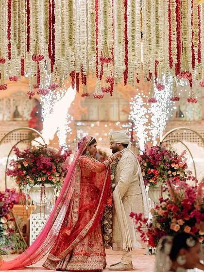 The couple shares their varmala moment under a shower of petals and gentle pyrotechnics. The mandap, with its cascading florals, provides a stunningly romantic frame for this key ritual.