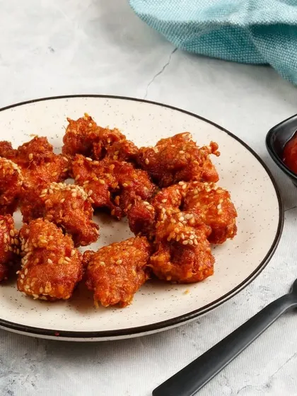 Another view of our bite-sized Popcorn Chicken, showcasing the crispy coating and sesame seed garnish.