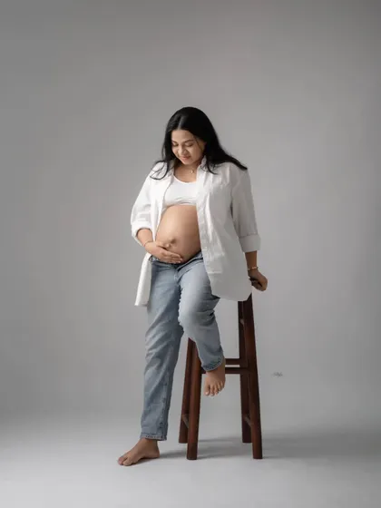 A full-length view of the casual bare-bump look, showing a confident and relaxed pose by the mother-to-be.