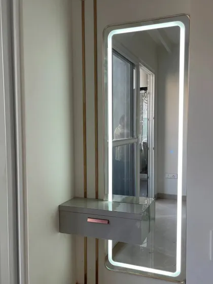 A sleek, wall-mounted dressing unit. The design includes a tall, rectangular mirror with an LED border and a small floating drawer, perfect for compact spaces.
