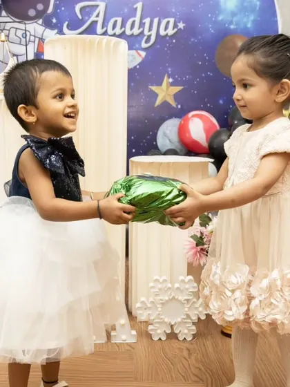 The joy of giving and receiving. This photo captures a lovely interaction between two young guests at a child's birthday party.