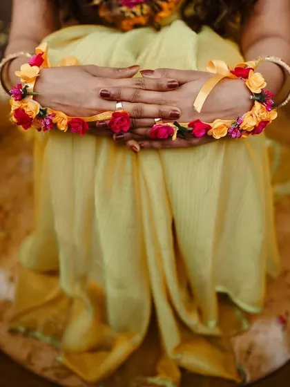 A detailed shot of the bride's hands adorned with floral jewelry during her Haldi ceremony. We pay attention to the small details that add beauty and significance to your day.