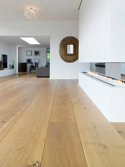 Here, a very light-colored wood floor complements a minimalist interior with a modern fireplace. The seamless, clean look of the floor is essential to achieving this uncluttered and contemporary aesthetic.
