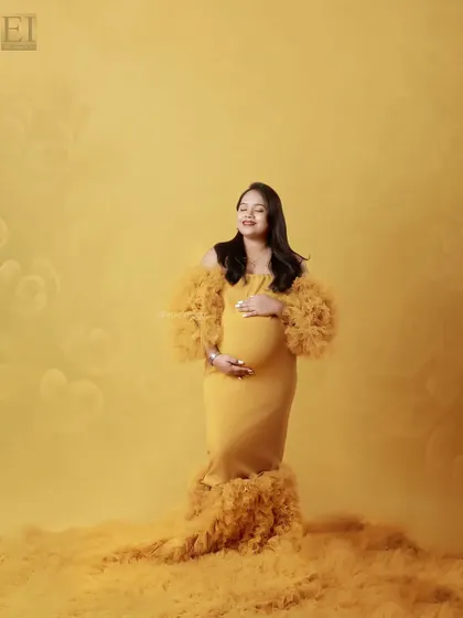A serene moment captured in the studio, with the mom-to-be in a yellow gown, eyes closed and smiling.