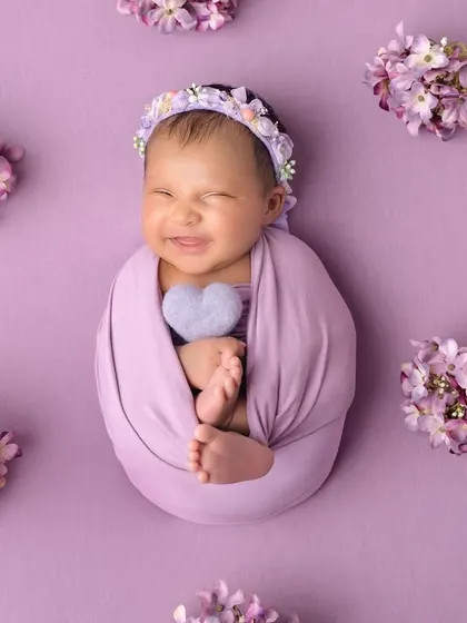 A big, happy grin from this swaddled newborn! Surrounded by lavender flowers, this photo is pure, simple joy.