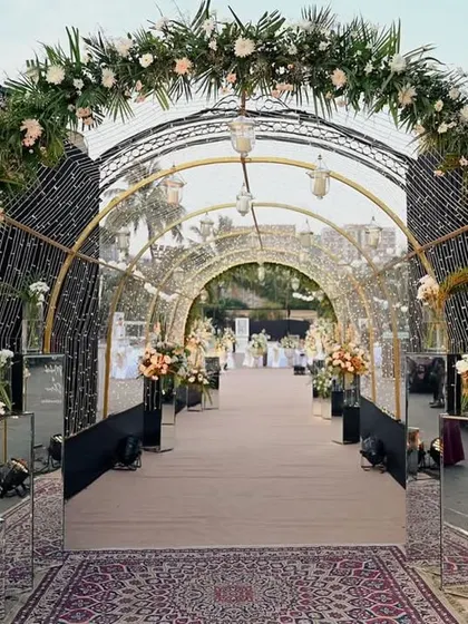 A dramatic and glamorous entrance tunnel with black floral arches and sparkling lights, leading to the main event area.