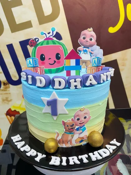 A sweet 2kg Cocomelon cake for a first birthday, with colorful fondant blocks spelling out the name.