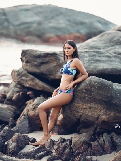 A beautiful portrait of a model in a floral bikini, posing against the rocks. The colors of the bikini pop against the neutral tones of the natural background.