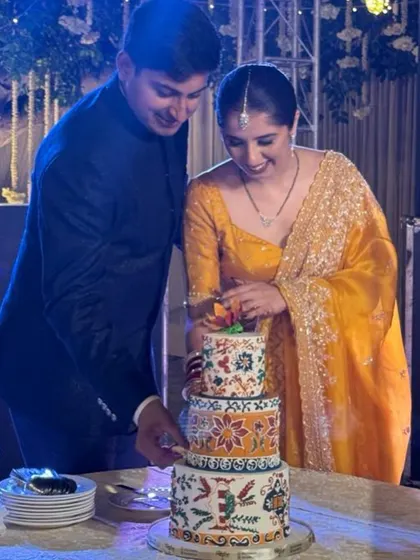 The happy couple cutting into their beautiful and unique Rangoli wedding cake.