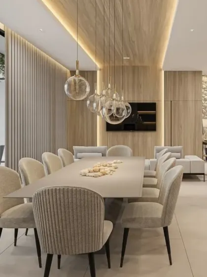 This open-plan dining area combines natural textures like wood paneling and a stone accent wall. The design seamlessly blends the dining and living spaces, unified by a neutral color scheme and warm, ambient lighting.