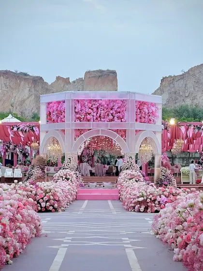 A wide view of the pink mandap, showcasing the aisle lined with thousands of flowers and the elegant structure set against the rugged landscape. It was a beautiful contrast of nature and design.