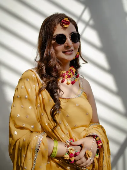 A happy, sun-kissed portrait of the bride-to-be. The sunglasses add a fun and modern twist to the traditional Haldi look.